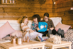 Three siblings sat in a garden room watching TV on an iPad.
